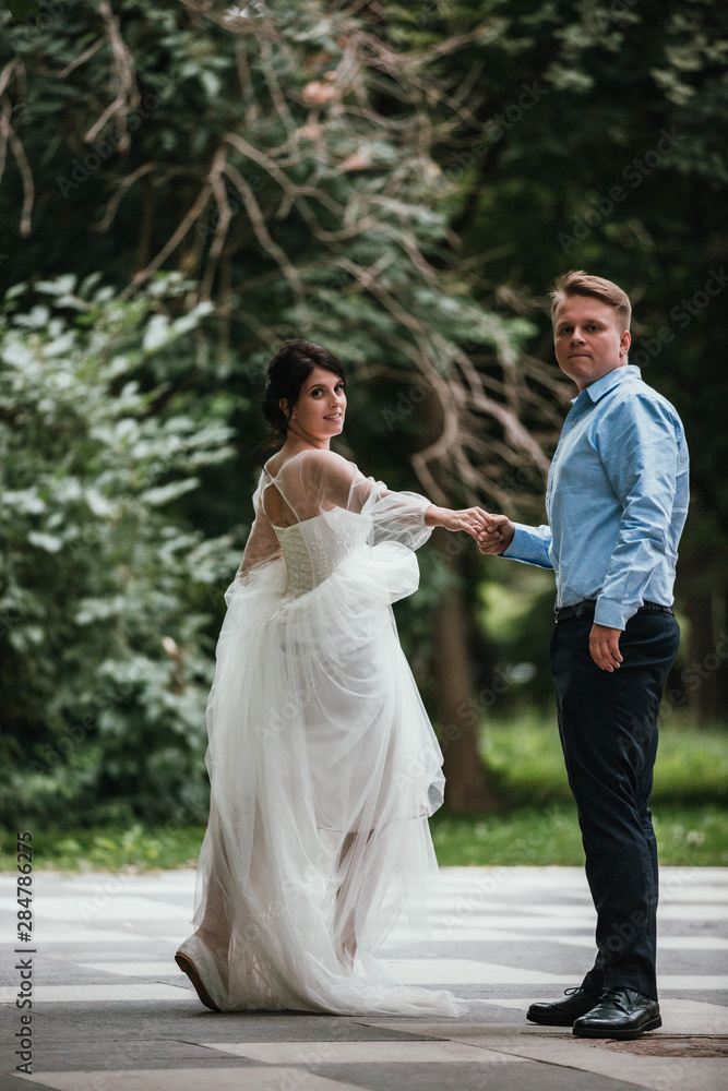 Rear view of a newlywed couple hugging in a park. Couple goes into the distance. Rear view of a newlywed couple hugging in a park. Couple goes into the distance.