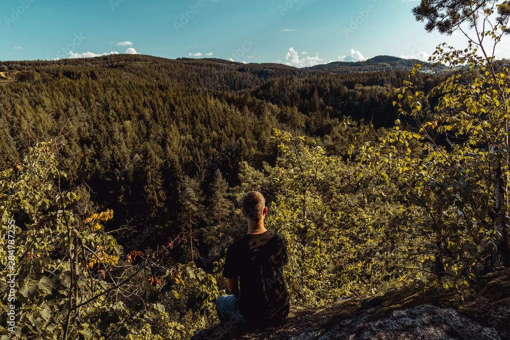 Young man sitting and looking to nice summer valley, Czech republic Young man sitting and looking to nice summer valley, Czech republic