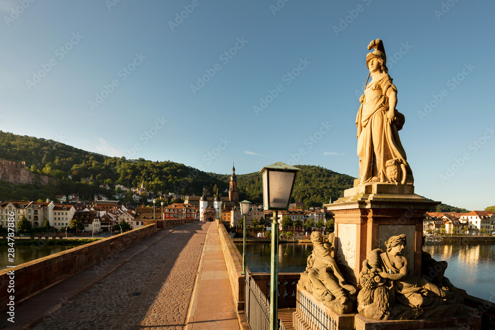 Minerva Denkmal auf der alten Brücke in Heidelberg mit Blick auf die Altstadt im Morgenlicht