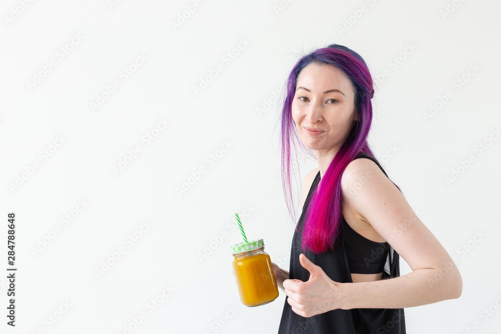 Cute young mixed race hipster girl with colored hair drinks fruit smoothie before starting a yoga class on a white background with copy space. Healthy lifestyle concept. Copyspase. Cute young mixed race hipster girl with colored hair drinks fruit smoothie before starting a yoga class on a white background with copy space. Healthy lifestyle concept. Copyspase.