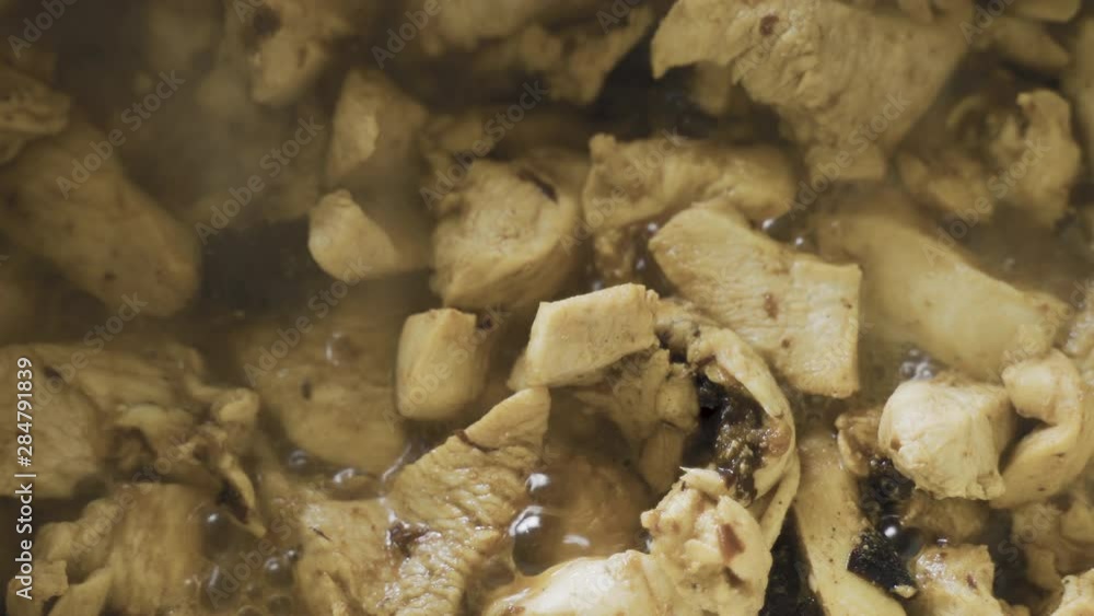 Sliced chicken with prunes fried and gurgle in sauce during cooking. Close up. View from above. Top view Sliced chicken with prunes fried and gurgle in sauce during cooking. Close up. View from above. Top view