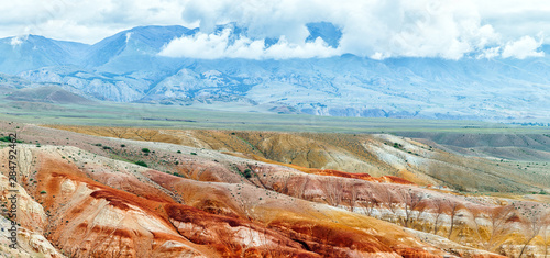 A stunning panorama of a mountain chain of peaks, a canyon with red clay against a stunning view of the sky and clouds, top view. Mars fields in Altai, Russia photo