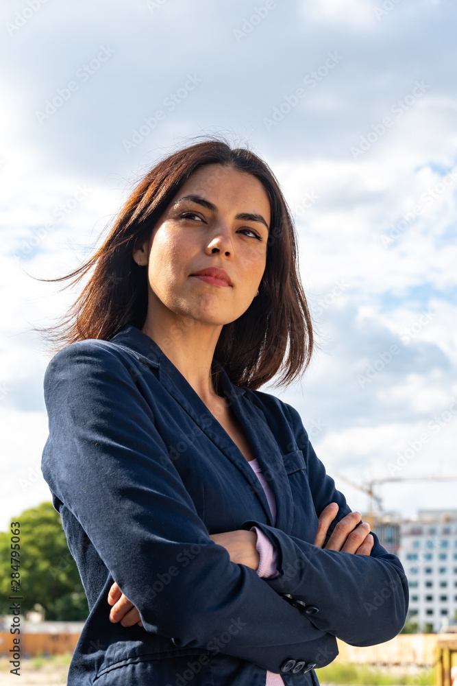 Low angle portrait of a young businesswoman standing outdoors and crossing her arms. Low-angle shot