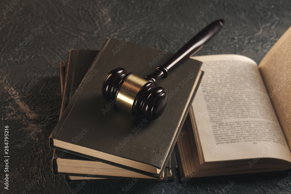 Law concept - Open law book with a wooden judges gavel on table in a courtroom or law enforcement office on black background. Law concept - Open law book with a wooden judges gavel on table in a courtroom or law enforcement office on black background.
