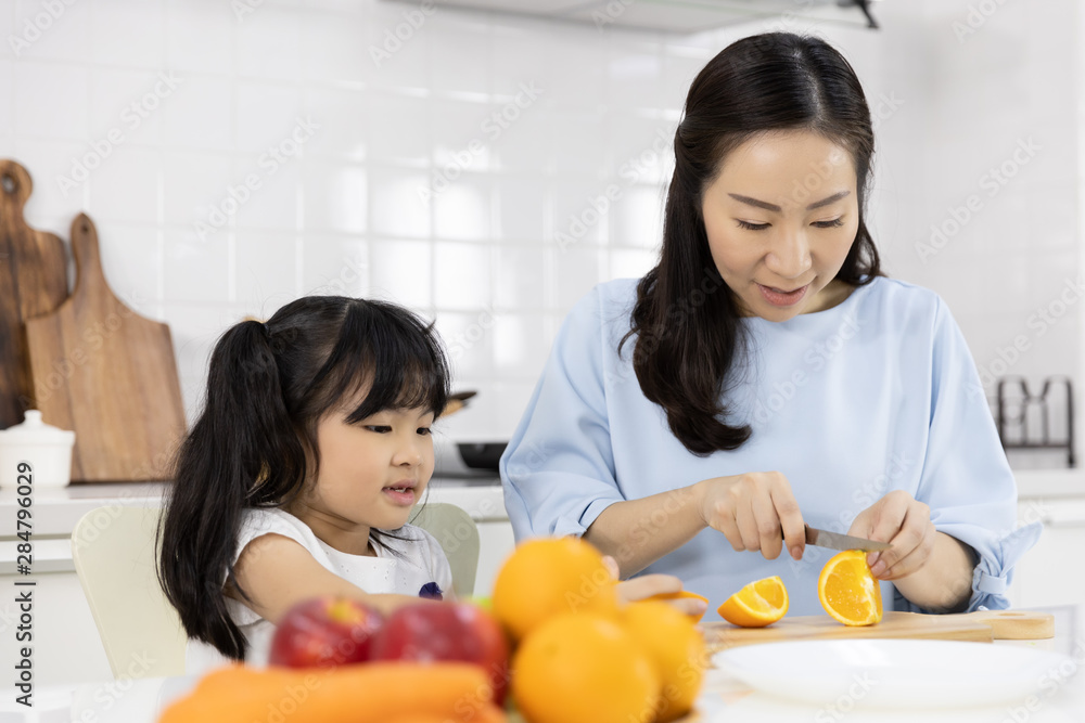 Happy Asian family Little girl enjoy and Mother are preparing the vegetables and fruit in the kitchen at home. Healthy food concept