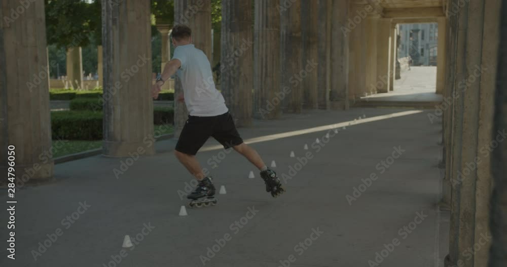 Handsome Europian man skating and doing cool tricks on roller skates in white blue t-shirt at city downtown location.Artistic improvisation of professional skating and spinning tricks.Camera following Handsome Europian man skating and doing cool tricks on roller skates in white blue t-shirt at city downtown location.Artistic improvisation of professional skating and spinning tricks.Camera following