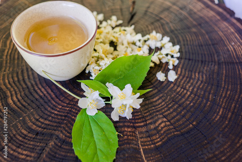 Cup of green tea, dried  blossoms and sprig of jasmine on wooden board