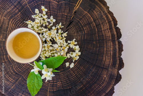 Cup of green tea, dried  blossoms and sprig of jasmine on wooden board. Flat lay with copyspace