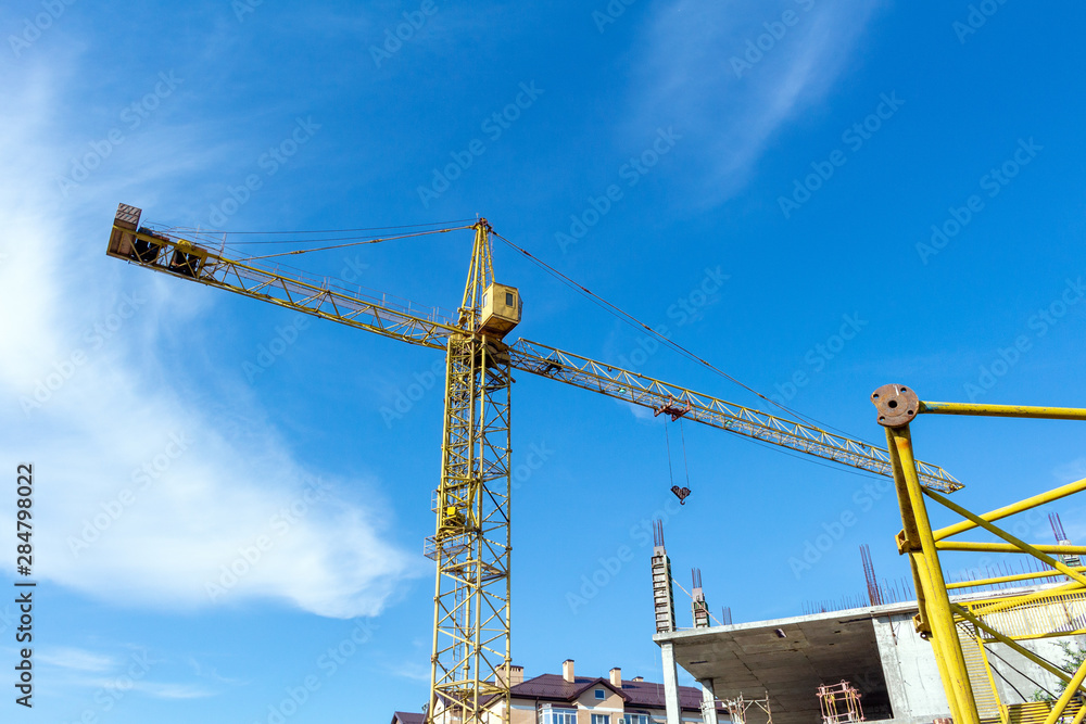 Tower crane on the blue sky background. Building construction work concept, investments in the development construction buildings and structures industry.