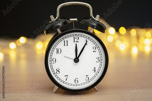 Close up of retro alarm clock on blurred Christmas background with bokeh