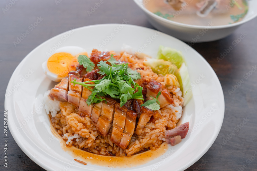 Close up rice crispy pork, roasted red pork, Scallion and boiled egg with sauce in white plate on wooden table background. Close up rice crispy pork, roasted red pork, Scallion and boiled egg with sauce in white plate on wooden table background.