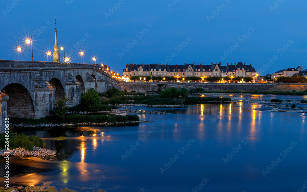 Twilight view of Jacques Gabriel bridge and city skyline reflected in water of Loire river. Blois, France.