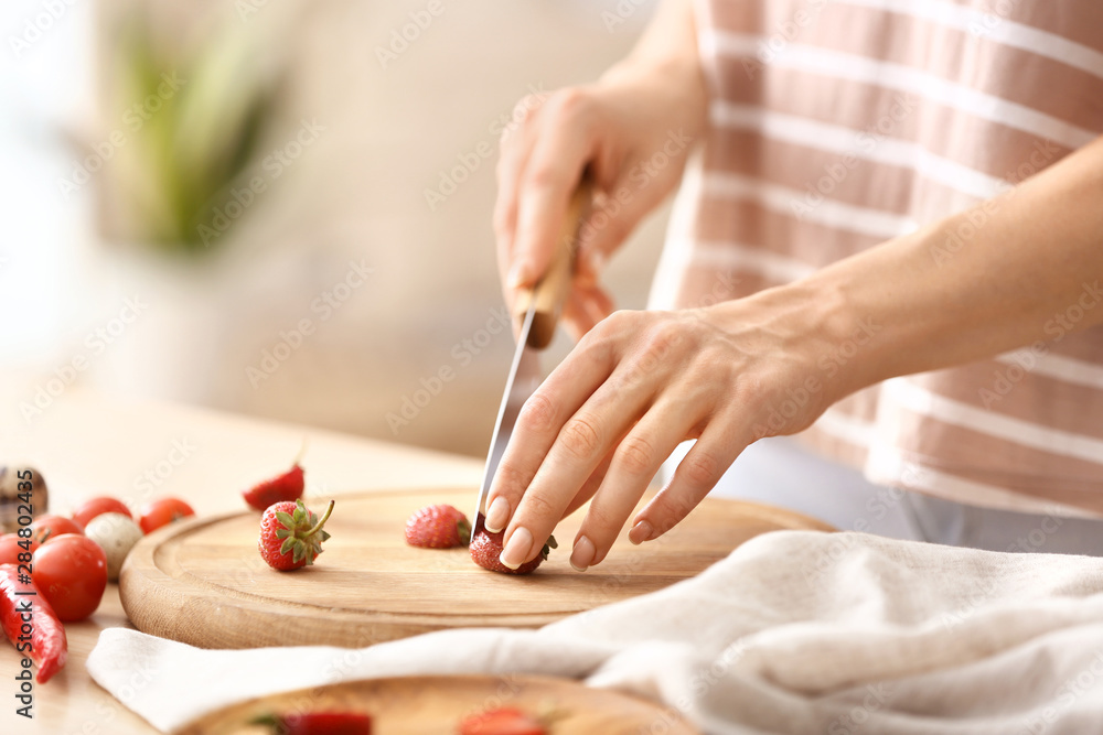 Woman cutting fresh strawberry at table