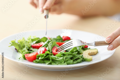 Woman eating fresh salad with strawberry and spinach at table, closeup