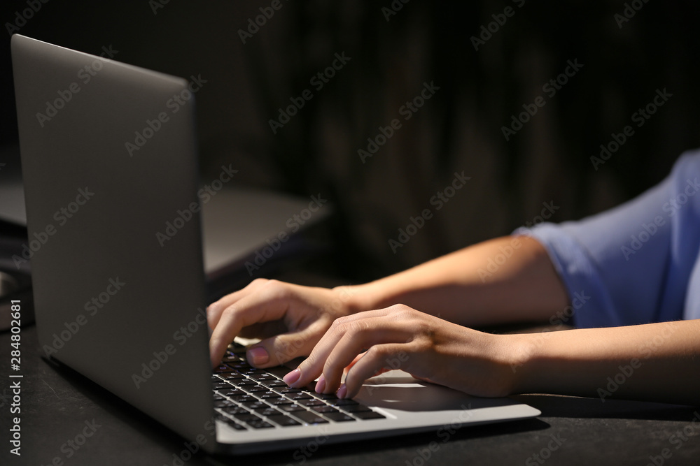 Woman working on laptop at table in evening, closeup Woman working on laptop at table in evening, closeup