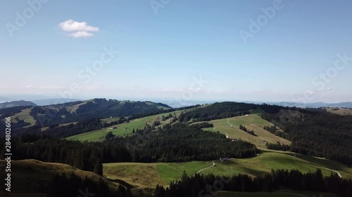 Fly over aerial shot of partially cleared paddocks with some forest and mountains in the background. Sattelegg, Switzerland. photo