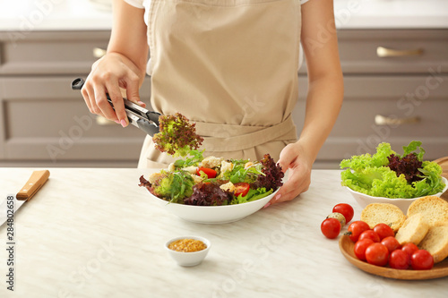Woman preparing tasty salad in kitchen