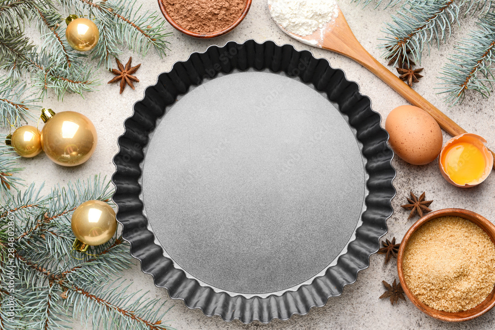 Baking pan with ingredients for Christmas pie and decor on grey background