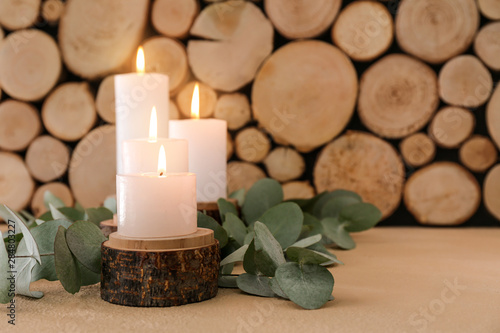 Beautiful burning candles and eucalyptus branches on wooden background