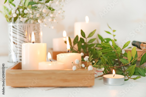 Beautiful burning candles and floral decor on table