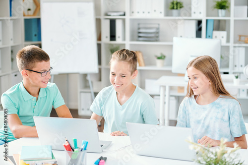 Group of contemporary schoolkids watching online video on laptop