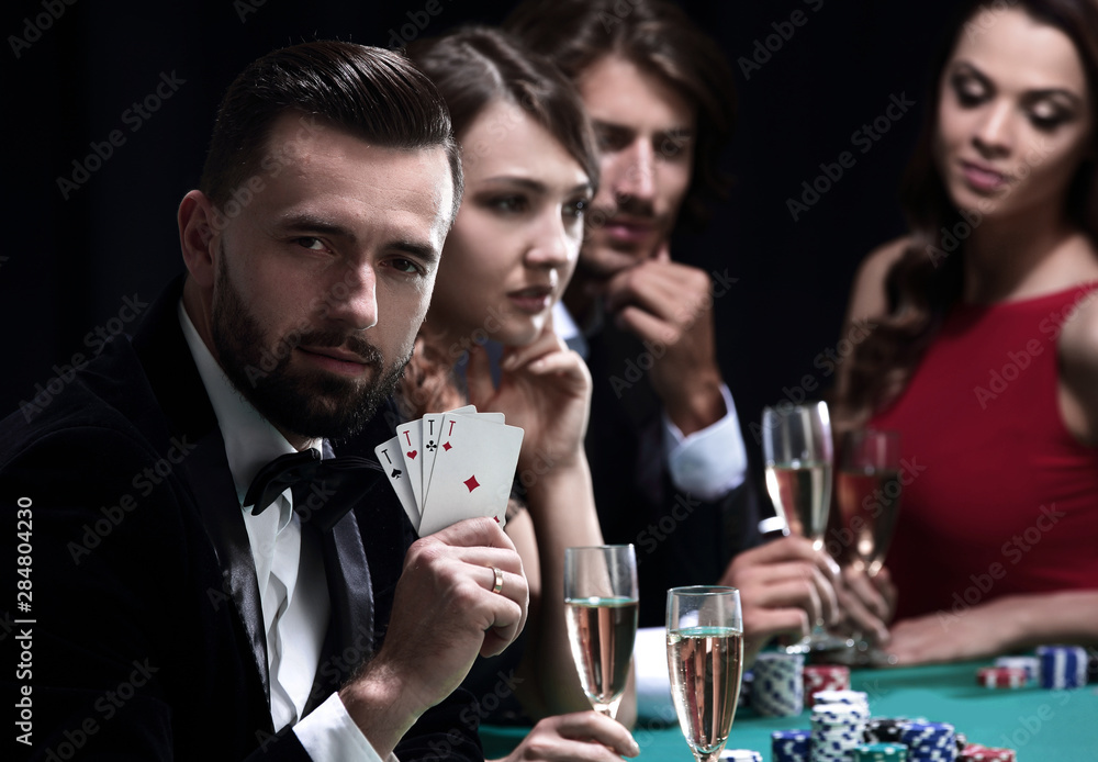 Poker player to four aces over dark background