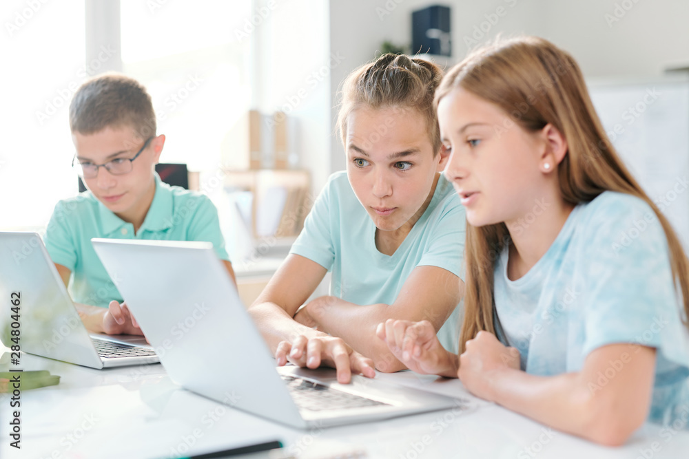Middle school boy and girl looking at curious stuff on laptop display Middle school boy and girl looking at curious stuff on laptop display