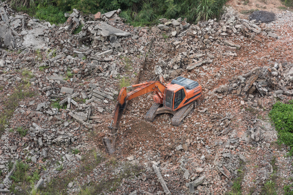 Aerial view of an orange large excavator striking a gravel while working in the field Aerial view of an orange large excavator striking a gravel while working in the field