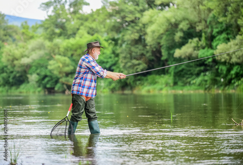 Mature man fishing. Retired fisherman. Male leisure. Fisherman with fishing rod. Activity and hobby. Fishing freshwater lake pond river. Happiness is rod in your hand. Senior man catching fish