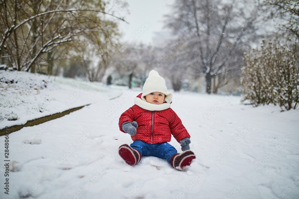 Happy smiling baby girl sitting in snow