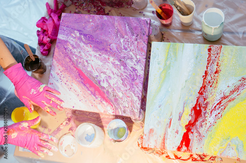 Print op canvas Creative woman painter teaching three female student creating fluid acrylic abstract painting in art therapy class, with table full of bottle with defferent paint colors