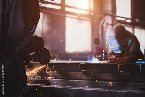 A welder with a welding machine works in a factory