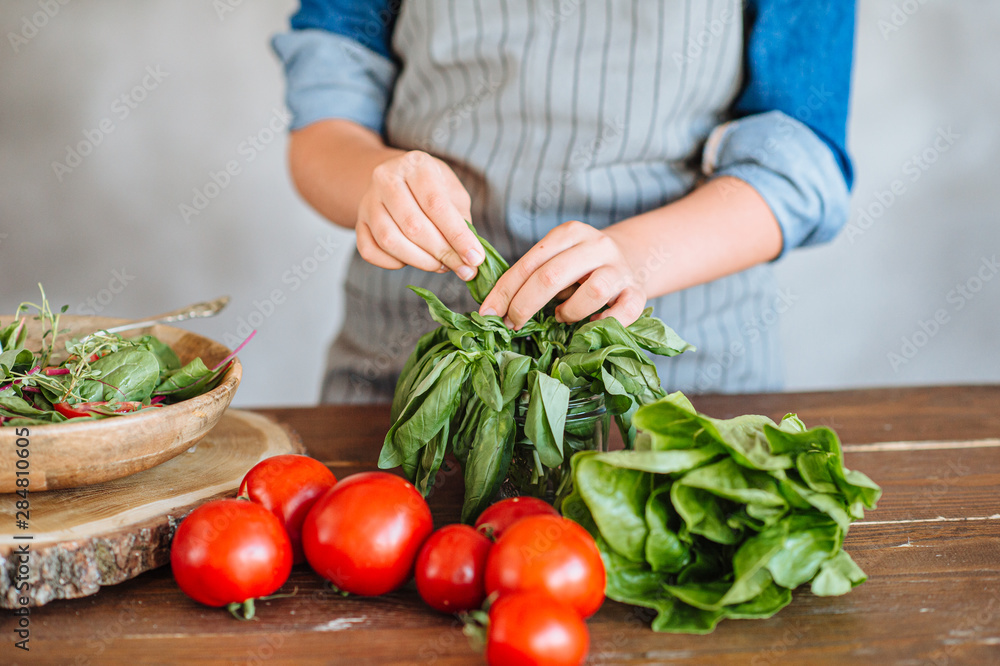 woman cooking salad with green leaves, mozzarella and tomatoes on the wooden table and wooden plate woman cooking salad with green leaves, mozzarella and tomatoes on the wooden table and wooden plate