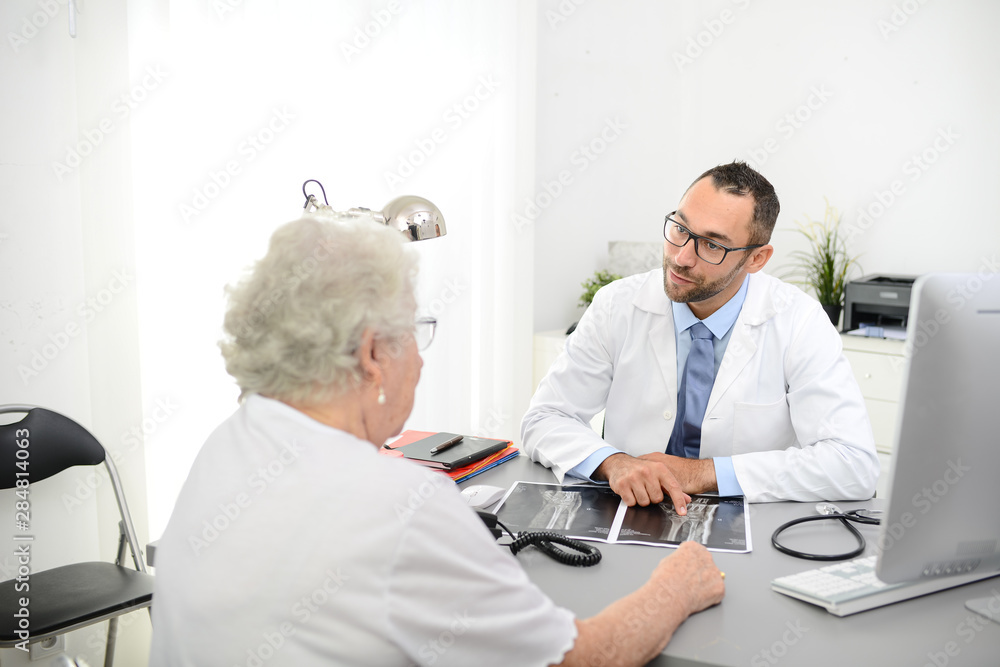 handsome doctor giving medical consultation diagnostic to elderly senior woman in hospital office handsome doctor giving medical consultation diagnostic to elderly senior woman in hospital office