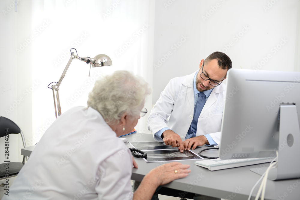 Obraz premium handsome doctor giving medical consultation diagnostic to elderly senior woman in hospital office