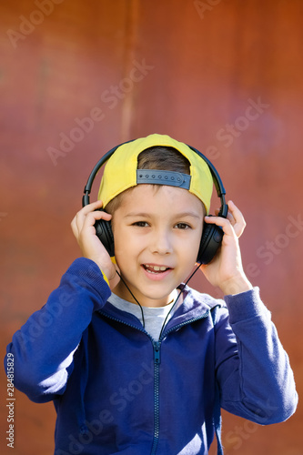 Young boy in headphones listening to modern music on an urban street. Child likes the song. © alexeytsurkan