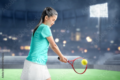 Asian woman with a tennis racket in her hands hit the ball