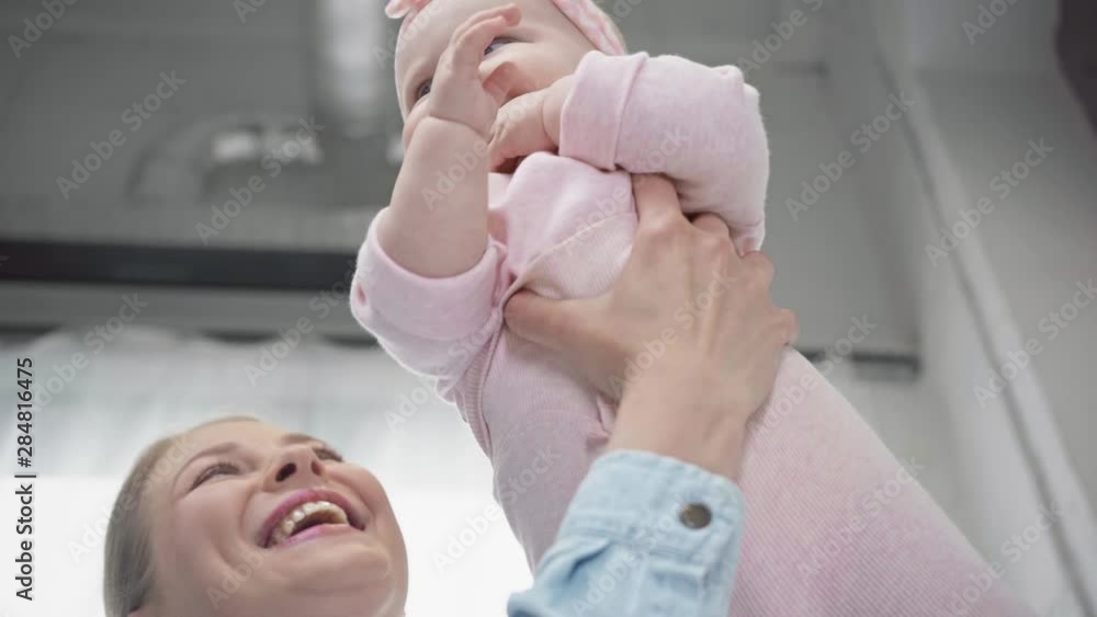 low angle view of mother holding in arms cheerful infant low angle view of mother holding in arms cheerful infant