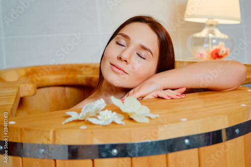 Woman having spa treatment and relaxing in wooden hot barrel sauna, cedar bathtub photo