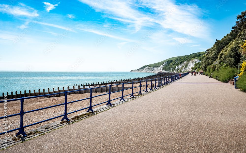 Eastbourne promenade, East Sussex, England. A bright, summer view west along the sea front towards the white chalk cliffs and South Downs.