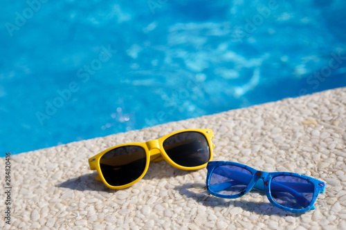 Sunglasses lie on the background of the pool. Family travel. The best holidays for adults and children.