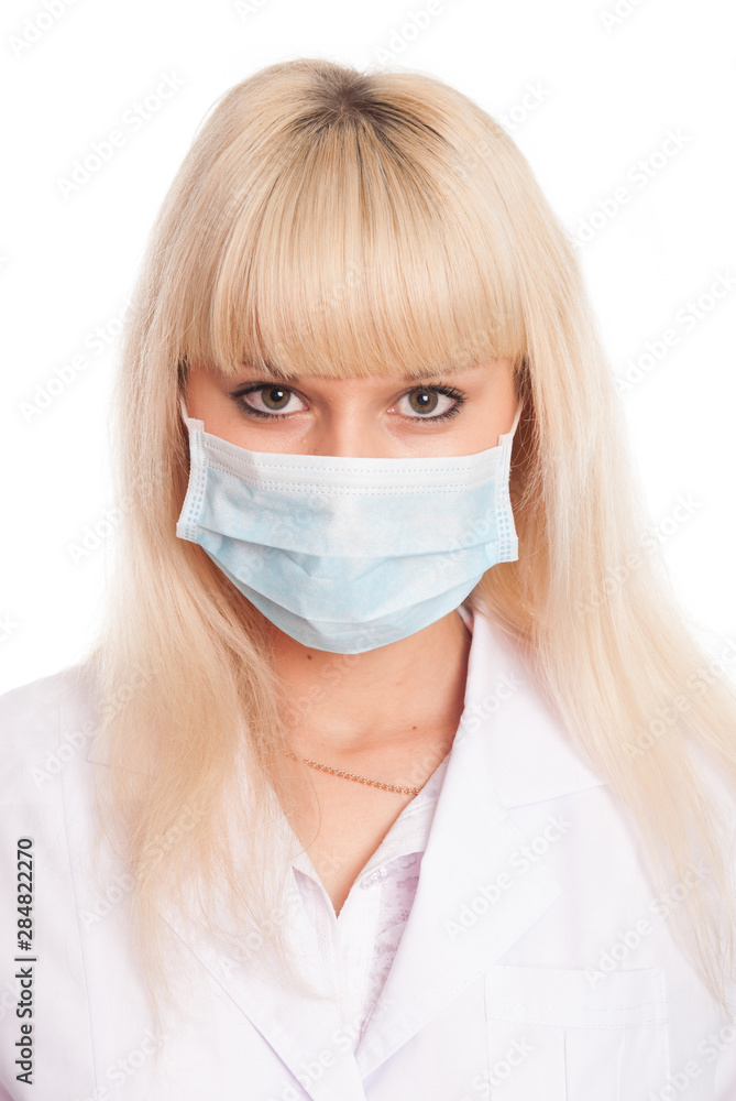 Close up of a young female nurse in mask looking at the camera.
