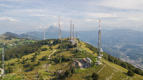 Drone aerial view of a group of towers for telecommunications  television broadcast  cellphone  radio and satellite on Linzone mountain peak. Electromagnetic and environmental pollution. Italian Alps