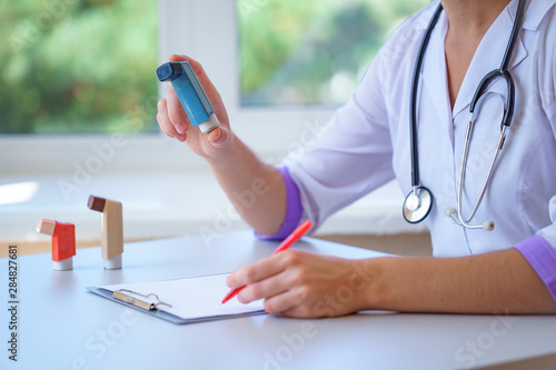 Canvastavla Doctor writes prescription for asthma inhaler to asthmatic patient during medical consultation and examination