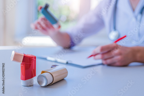 Doctor writes medical prescription for asthma inhaler to asthmatic patient during medical consultation and examination in hospital. Healthcare photo