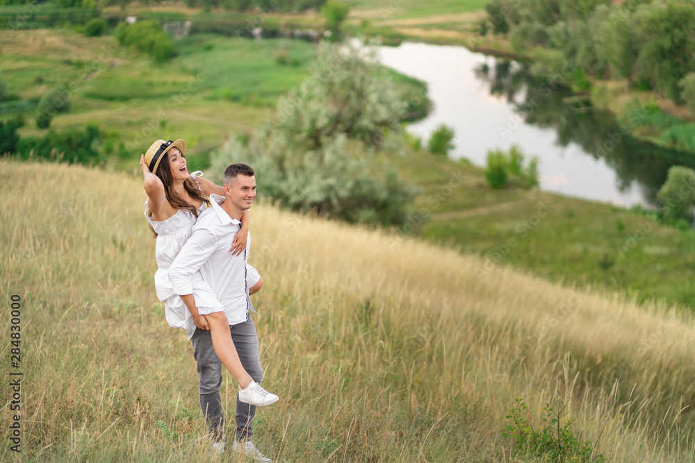 Couple in love. Boyfriend carrying his girlfriend on piggyback. Love and tenderness, dating, romance. Lifestyle concept