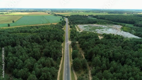 Aerial View of City Garbage Dump in the Green Forest near Car Road in Summer. Ecology Problem of Environmental Pollution by Piles of Trash, Rubbish and Litter. Long 4K Drone Fly Over Shot photo