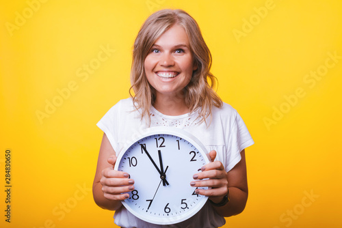 Portrait of cheerful young woman holding big white wall watch