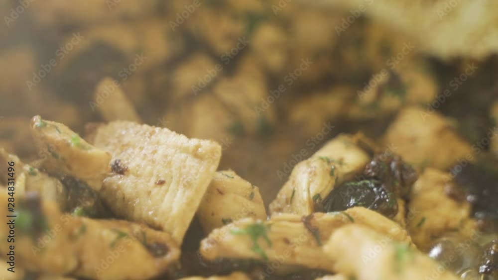 Slices of chicken with prunes and dill and gurgle in the sauce during cooking. Close up. View from above. Top view. Handheld Shooting
