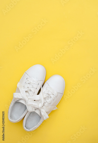 Pair of white sneakers on color background  top view